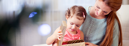 A mother watches her daughter open a gift