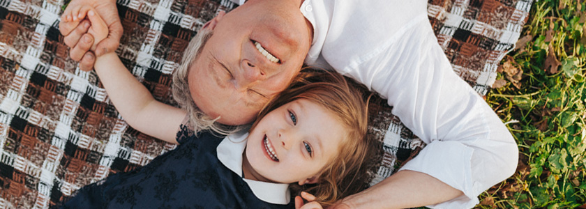 Grandfather and granddaughter playing on picnic blanket