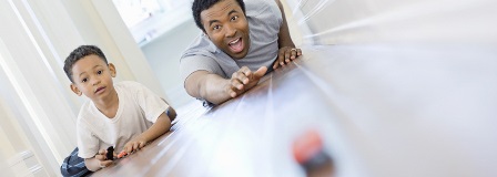 Father racing cars down a hallway with his son