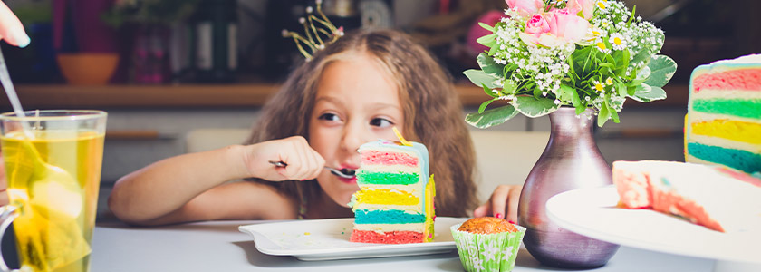 Girls enjoys big bite from big rainbow layered cake
