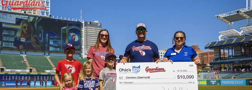 2024 Cleveland Guardian Home Run Winner Christen Eberhardt and family with their oversized college savings award check from Ohio's 529 Plan and Trisha Good.