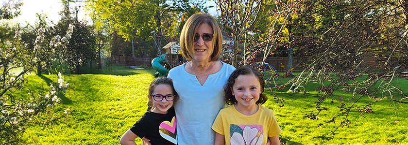 Grandmother poses in backyard with her two granddaughters