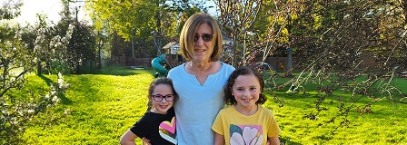 Grandmother poses in backyard with her two granddaughters