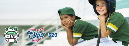 A young girl and boy dressed in green baseball jerseys watch a game.