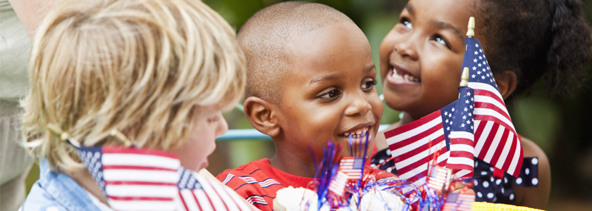 Three little kids hold American flags