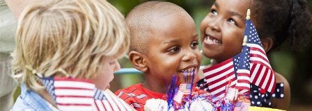 Three little kids hold American flags