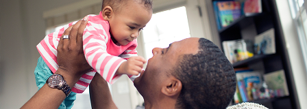 Dad smiles at his child who is staring at him.