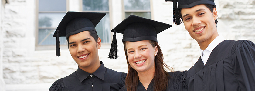 Three high school graduates in their caps and gowns pose for a picture