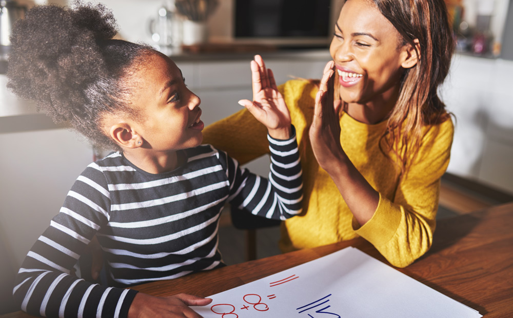 Mom high fives her daughter as she correctly completes math problem.