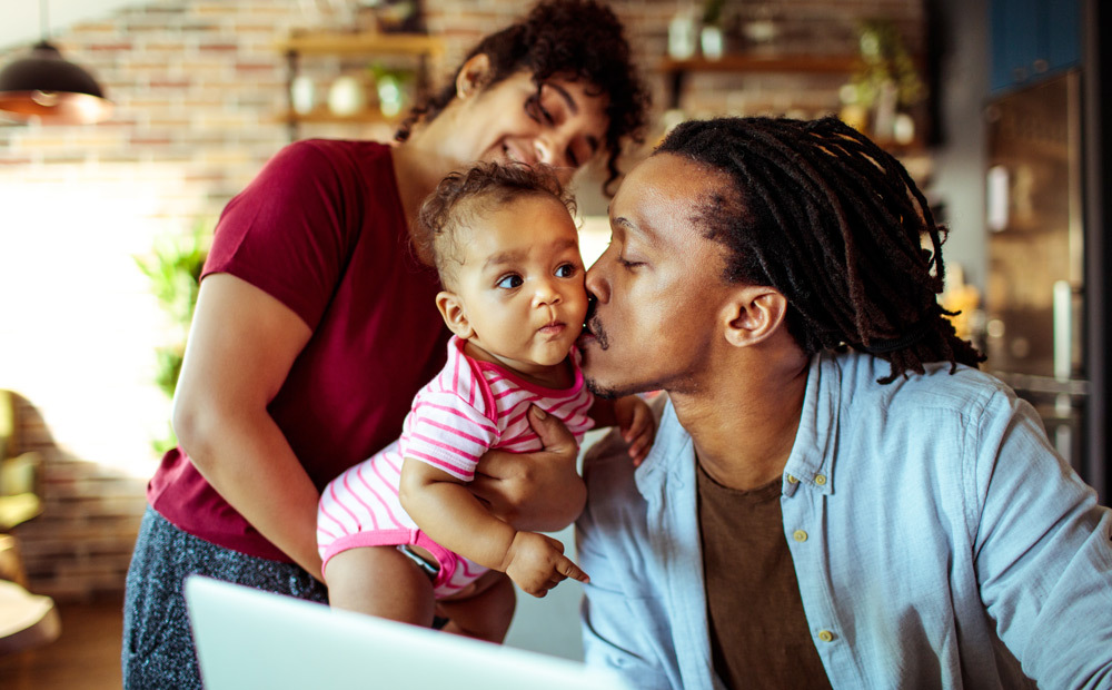 Dad kisses his baby who is being held the mom.